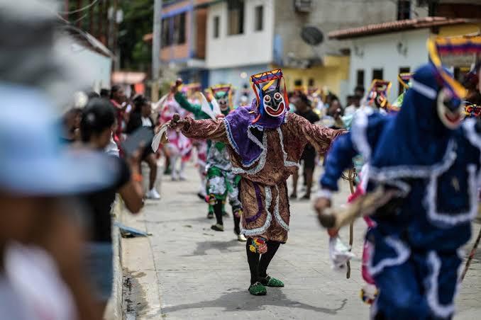 Diablos Danzantes con máscaras y trajes de colores bailando en la calle
